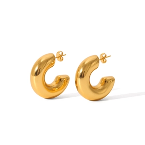 Macro detail of thick gold C-shaped hollow hoop earrings with a polished metallic finish