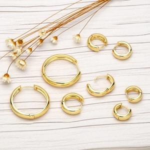 Polished gold round hoop earrings in various sizes displayed on a wooden surface