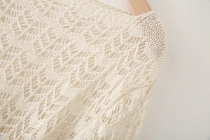 Macro detail of creamy crochet knit top showing intricate geometric diamond patterns