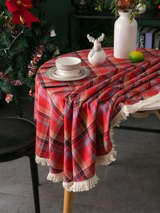 Close-up of red plaid cotton linen tablecloth featuring festive beige fringe tassels