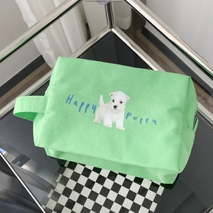 Close-up of light green puppy print canvas pouch with handle on a checkered surface