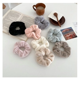 Close-up of soft faux rabbit fur scrunchies in various Morandi colors on a white desk