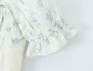 Détail de l'imprimé floral vintage ange et du poignet élastique à volants sur tissu blanc