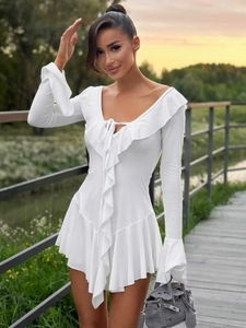 Détail d'une robe blanche à manches longues avec col en V, volants et taille ajustée en plein air