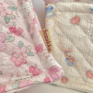 Detail of quilted fabric storage basket featuring floral patterns and woven brand labels
