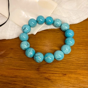Macro detail of turquoise beaded bracelet with natural brown veins on textured surface