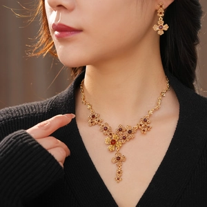 Close-up of a model wearing vintage gold flower necklace and earrings with red and yellow gems