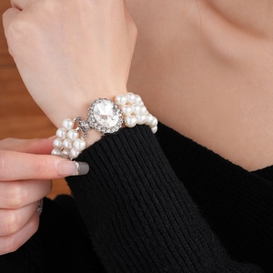 Dettaglio del bracciale di perle multistrato con chiusura ovale in strass sul polso