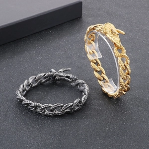Gold and black dragon head titanium steel cuban link bracelets on dark background