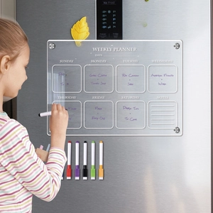 Macro shot of a child writing on a magnetic acrylic weekly planner on a refrigerator
