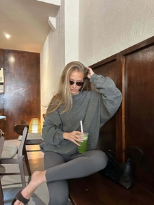 Vintage washed grey crewneck sweatshirt and leggings worn by model in a cozy cafe