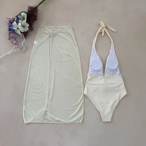 Flat lay of cream halter bikini set with matching mesh split maxi skirt and dry floral decor