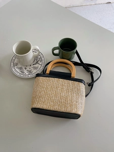 Minimalist straw bucket bag with wooden handle and black leather trim for women