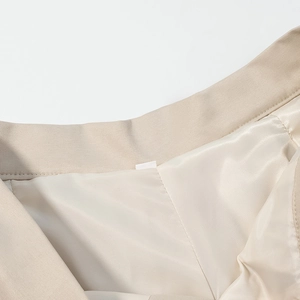 Detail view of beige high-waist shorts showing twill fabric and smooth satin lining
