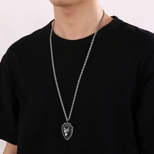 Close-up of a men's vintage silver lion shield pendant necklace worn on a black t-shirt