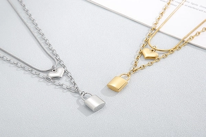 Close-up of double layer necklaces with heart and padlock pendants in gold and silver