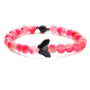 Macro detail of pink translucent beaded bracelet with a glittering blue butterfly bead