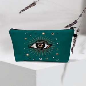 Detail of dark teal cosmetic bag with evil eye patterns on white concrete block