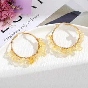 Detail of handmade bohemian earrings with gold wire and yellow natural stone chips