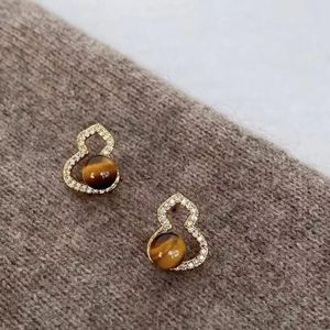 Macro shot of gold gourd earring featuring tiger eye stone and crystal inlay detail