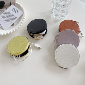 Collection of round leather coin purses in various colors on a minimalist white desk