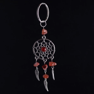 Detalle macro de llavero atrapasueños con piedra de cristal roja y colgante de pluma de plata