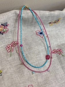 Detail of beaded turquoise and pink natural stone necklaces with gold lobster clasps