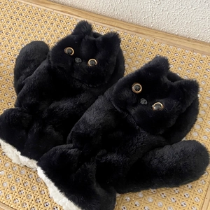 Close-up of black cat plush slipper with soft faux fur and golden bright eyes detail