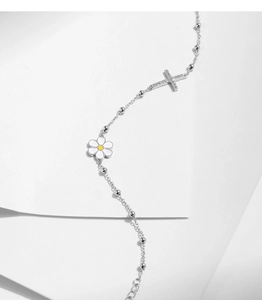 Detail of s925 silver bracelet featuring daisy charms and a sparkling diamond cross