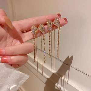 Gros plan de boucles d'oreilles nœud dorées avec strass brillants et longues franges