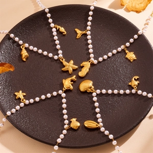 Pendentifs marins dorés sur colliers de perles blanches sur un plateau noir
