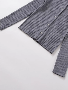 Macro detail of grey cable knit texture and polished decorative buttons on cardigan