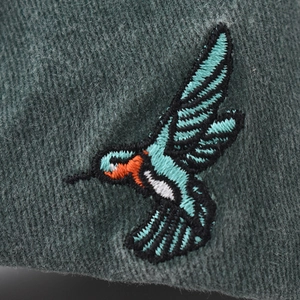 Washed cotton baseball cap featuring detailed hummingbird embroidery on deep green fabric