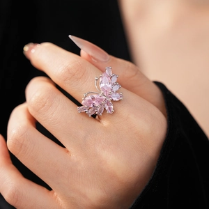 Gros plan détaillé d'une bague papillon argentée avec pierres marquises roses au doigt