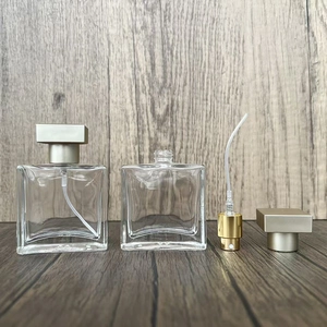 Flat square glass perfume bottle detail with golden sprayer pump and wood background