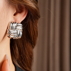 Close-up of silver knot-shaped metallic earrings worn by model for a trendy look