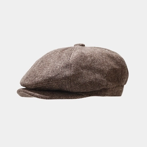 Detail of vintage brown herringbone newsboy cap showing wool blend texture and side profile