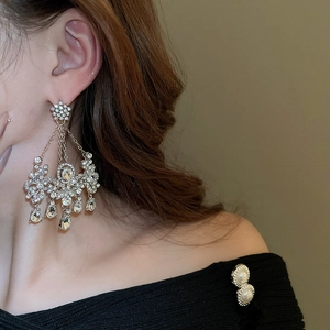 Détail de boucles d'oreilles fleur à pompons argentées avec cristaux sur un mannequin