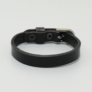 Detail of minimalist black leather bracelet featuring a metal buckle and adjustable holes