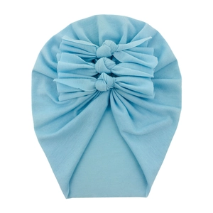 Detail of light blue baby turban hat with three bows made of soft knitted cotton
