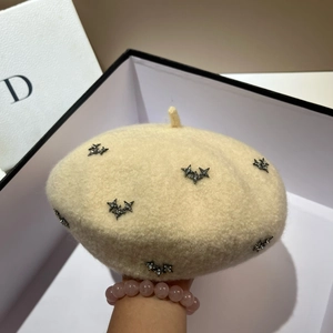 Close-up of beige fleece beret featuring sparkling metal star studs and a top tail design
