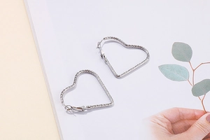 Vue détaillée des boucles d'oreilles cœur en argent avec textures gravées en métal