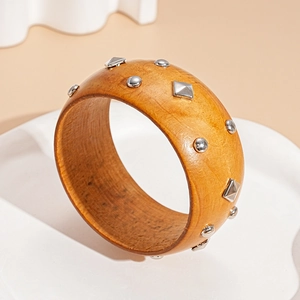 Detail of honey wood texture and silver metal studs on a retro minimalist bangle