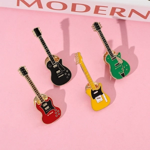Close-up of colorful electric guitar enamel pins in red black yellow and green on pink card