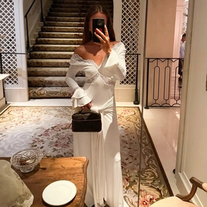 Detail of white V-neck dress featuring delicate lace trim and elegant ruffle flared sleeves