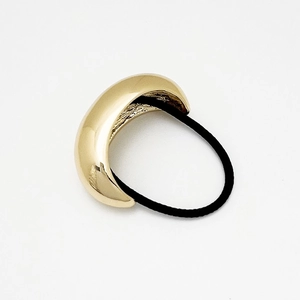Macro shot of polished gold metal ponytail cuff hair ring with black elastic cord