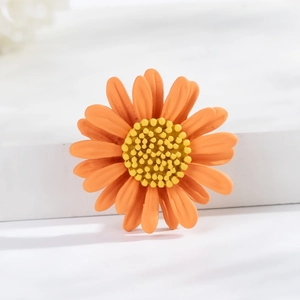 Macro shot of fresh orange daisy brooch with textured petals on a clean white display