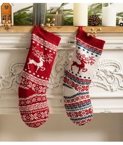 Red and white knitted Christmas stockings with reindeer patterns on a festive mantel