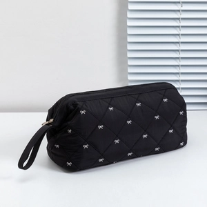 Detail of black quilted hair dryer bag with white bow embroidery and zipper closure