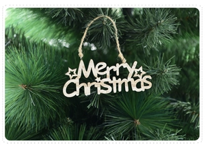 Detail of wooden Merry Christmas hanging ornament on a green pine tree branch